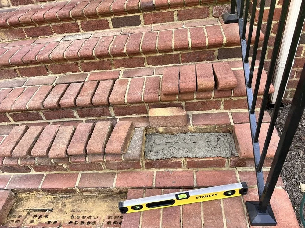 Brick-step repair in progress, with loose bricks lifted and mortar work visible